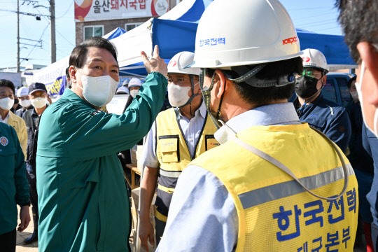 윤석열 대통령이 지난 9월7일 오후 제11호 태풍 힌남노로 피해를 입은 경북 포항시 남구 오천시장을 방문, 복구작업 중인 한국전력 관계자들과 대화하고 있다.<대통령실 제공·연합뉴스>